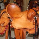 Rancher -2 strand barbed wire, straight-back, latigo wrap, saddlebags, stirrup leathers out, floral conchos, rope strap