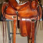 Rancher -basket weave border, dark straight-back, latigo wrap, floral conchos, stirrup leathers out, 3 in bell stirrups, rope strap