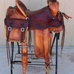 Trainer - 2tone, latigo, bags, back cinch, floral, leathers out, corner bskt wv, barbed wire w channels, breaststrap strap